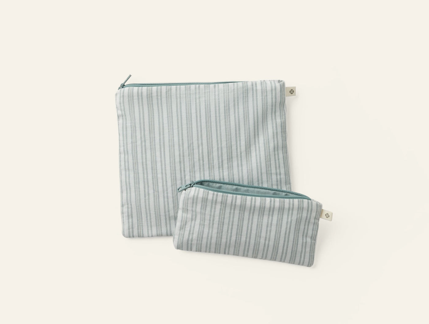 Close-up of two Coyuchi striped linen zip pouches in sage, large and small sizes.