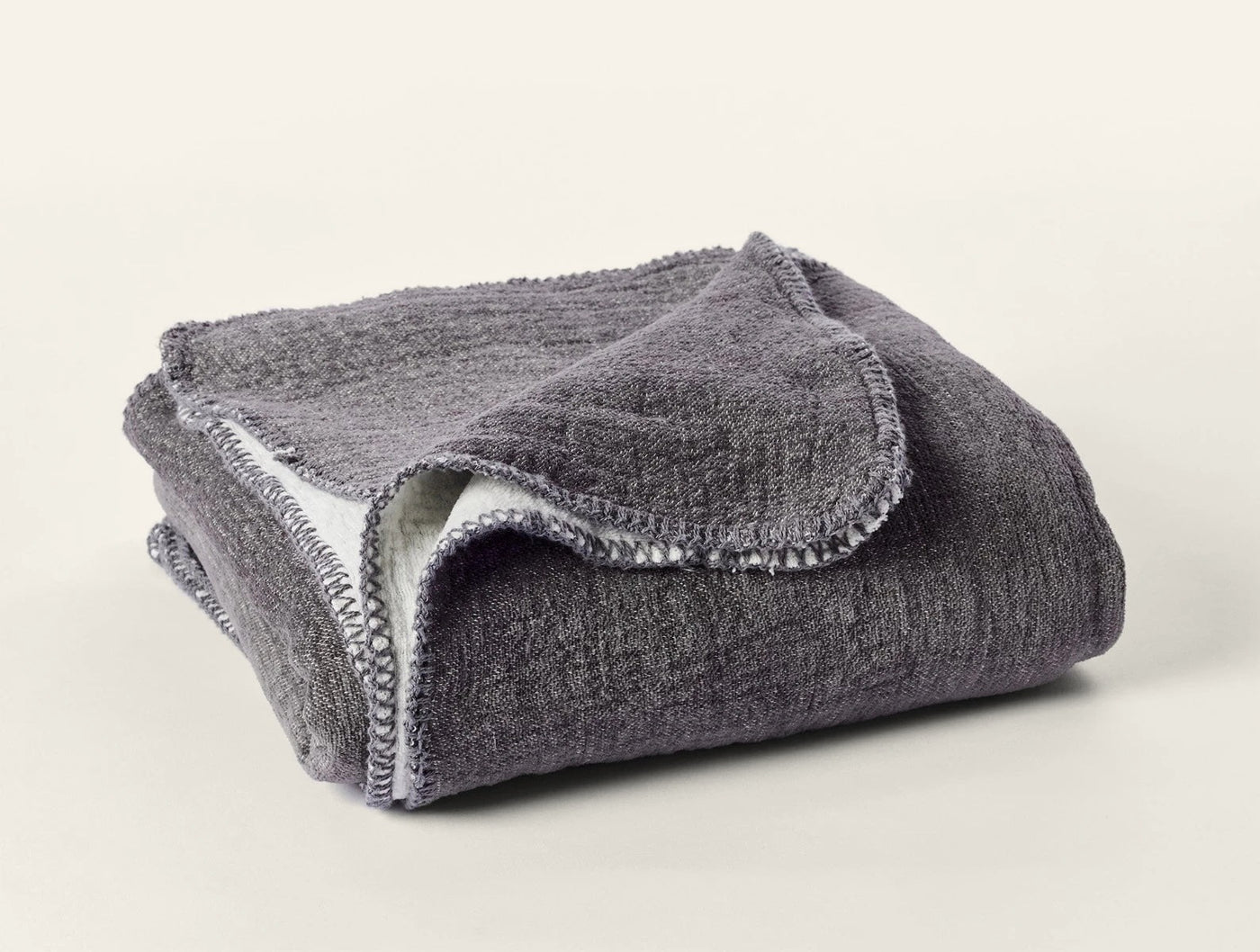 Folded charcoal Coyuchi Cozy Cotton Throw showing blanket-stitched edge detail.