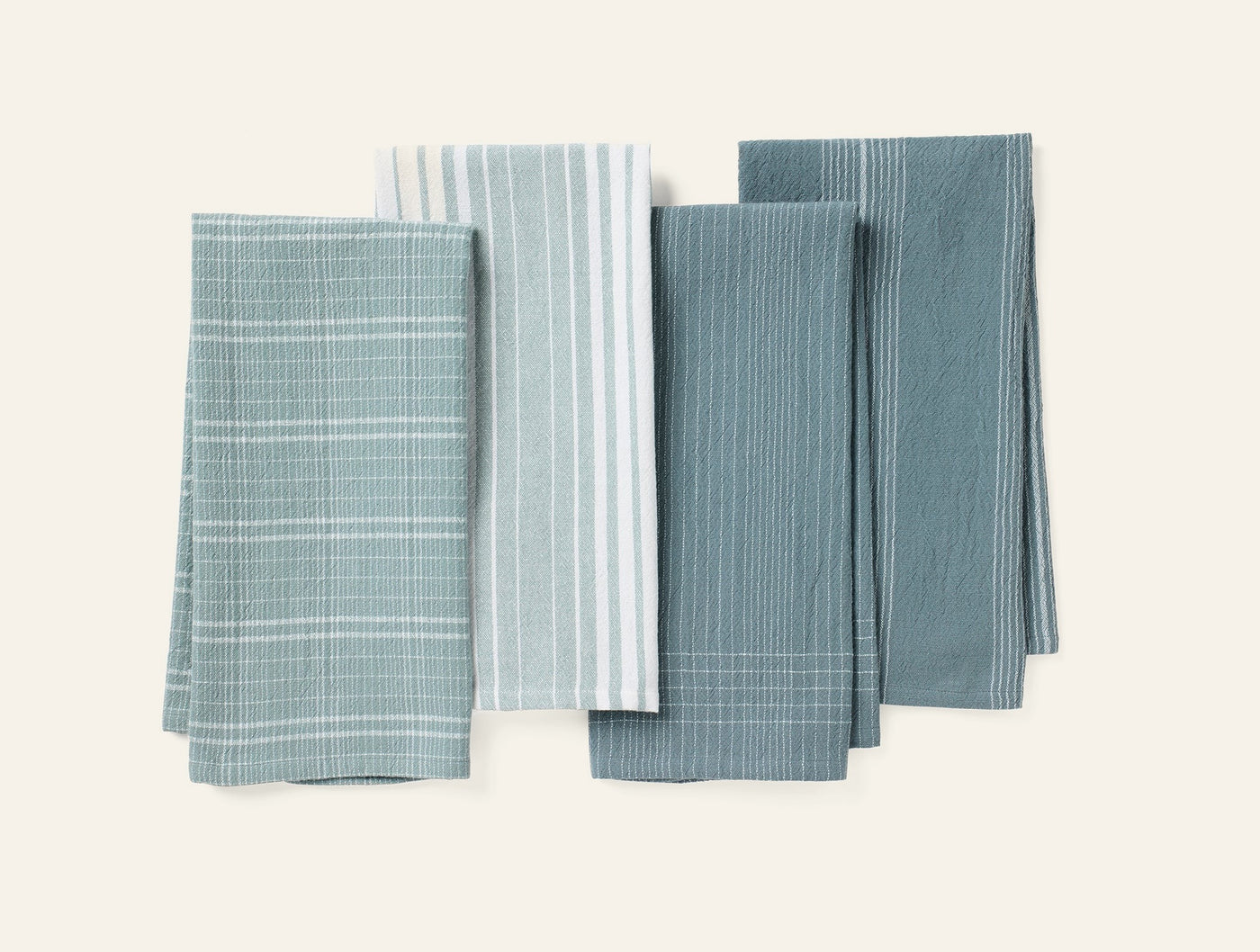 Coyuchi Fillmore kitchen towels in four muted teal patterns, flat lay arrangement.