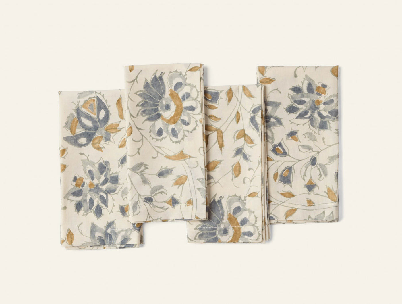 Coyuchi Flora Print napkins fanned out, ivory with slate and gold floral pattern.