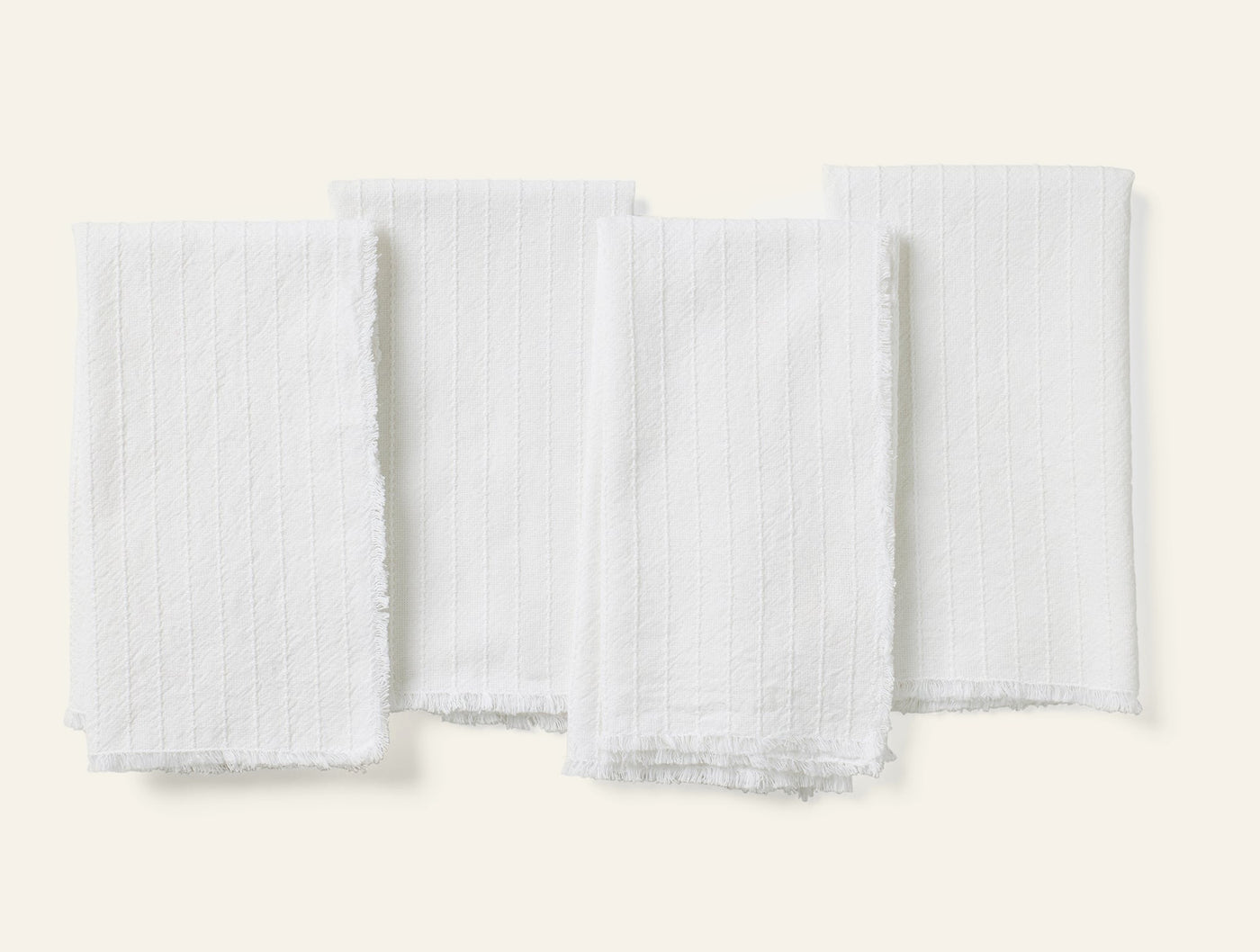 Coyuchi Fringe Stripe napkin set of four in white with ribbed texture and fringe trim.