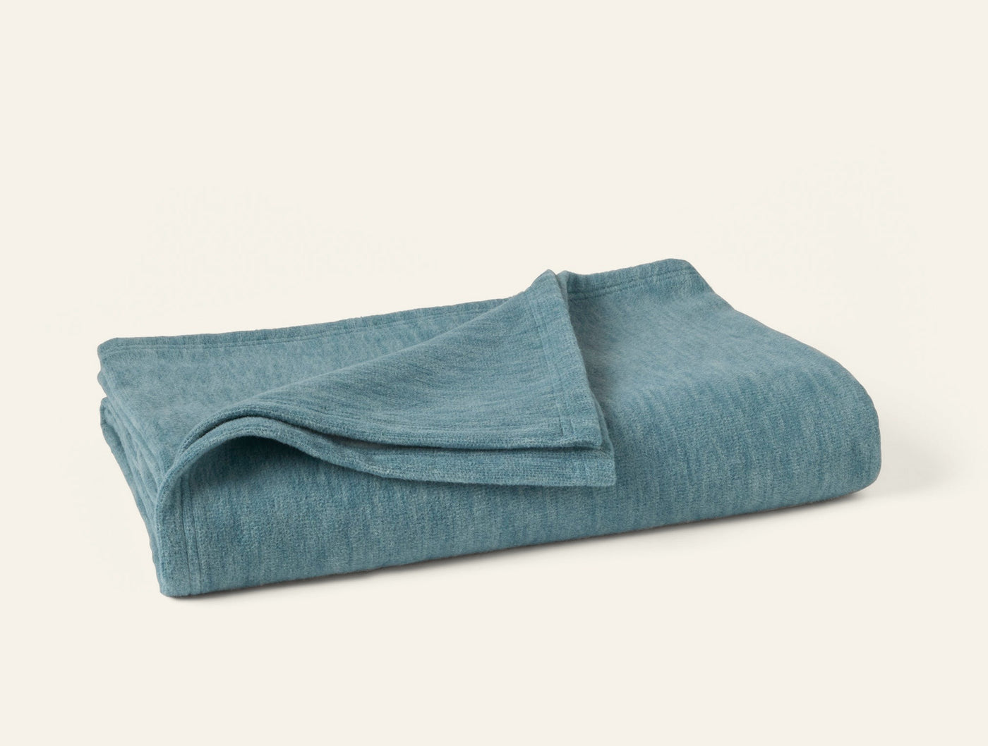 Coyuchi Full Circle Cotton Throw folded, heathered teal linen-weave texture visible.