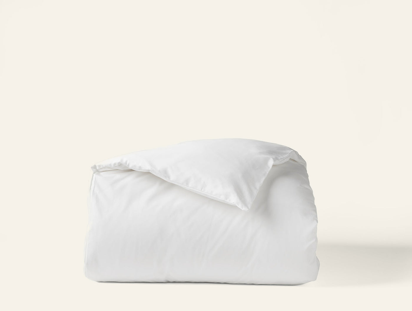 Coyuchi Heirloom Sateen duvet cover in white, neatly folded against a light background.