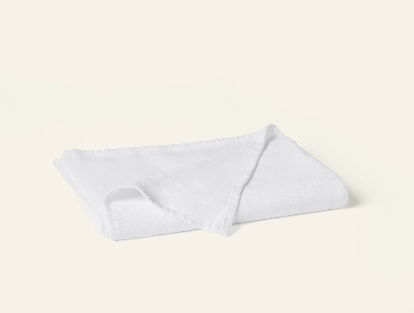 Coyuchi Helena Linen throw in white, folded flat showing fringe edge detail.