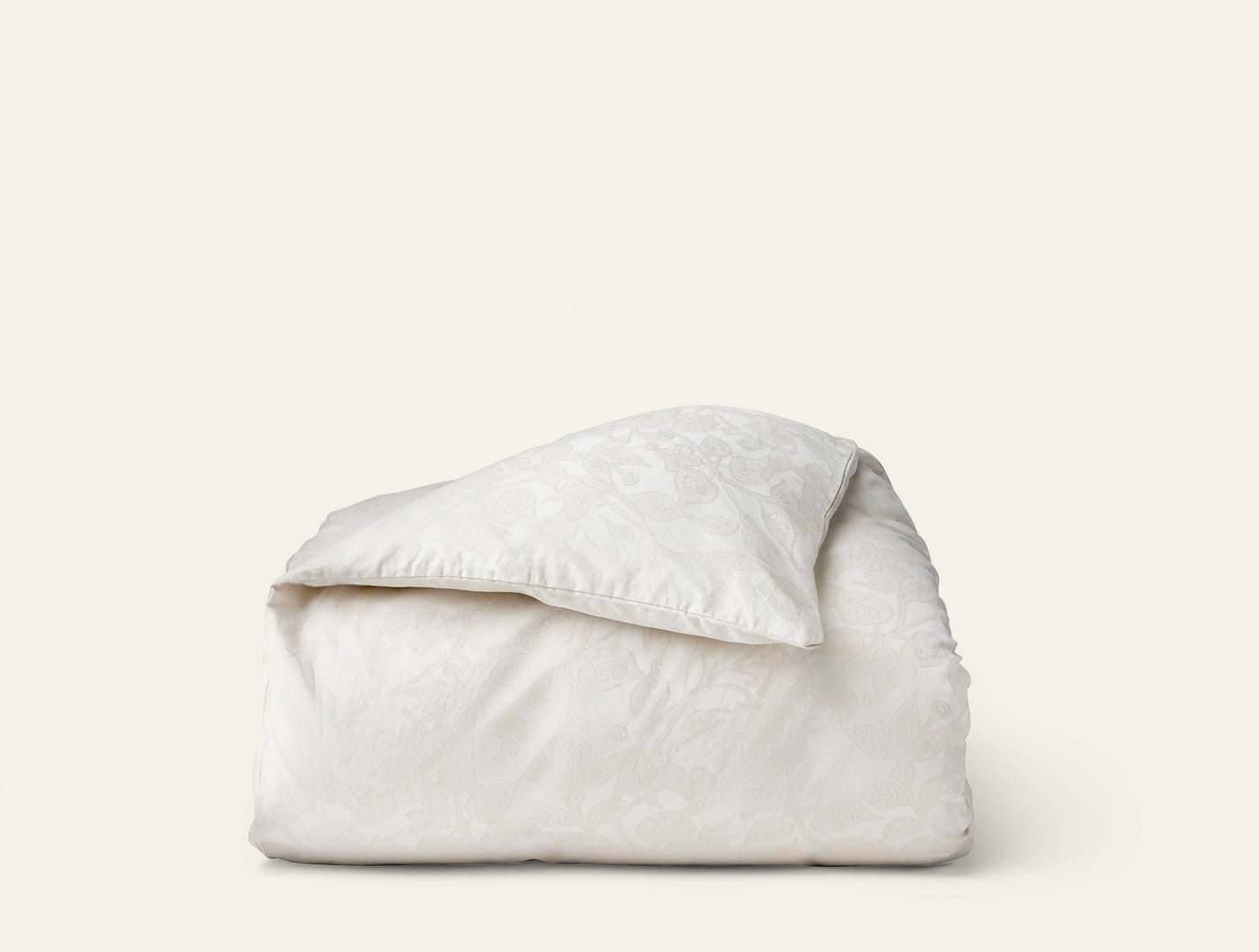 Coyuchi Heritage Percale Jacquard duvet cover folded, ivory with tone-on-tone floral pattern.