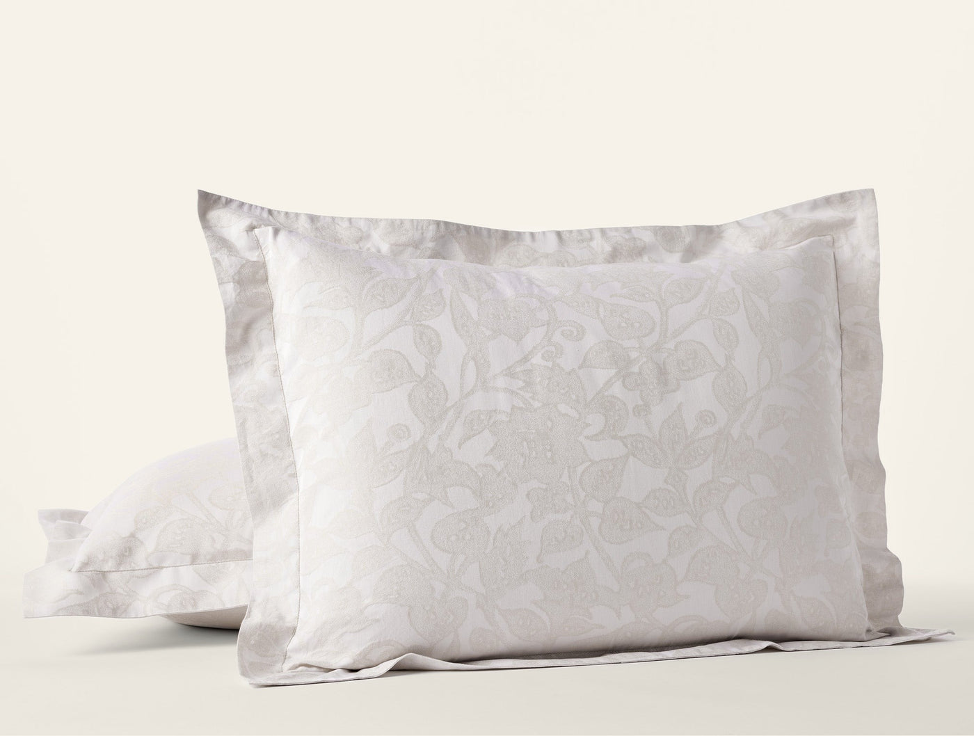 Close-up of Coyuchi Heritage Percale Jacquard shams in silver, floral woven pattern with flanged edge.