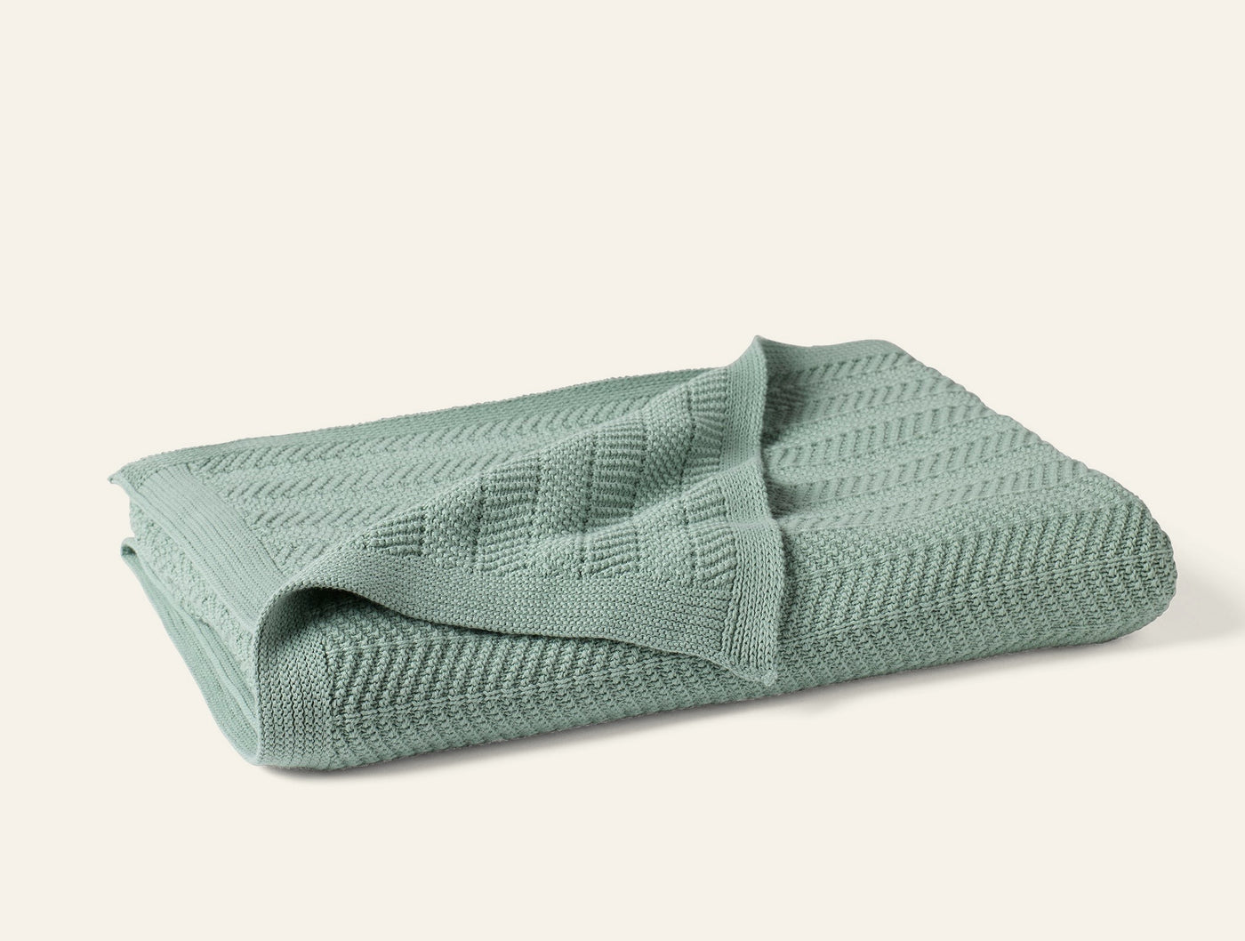 Coyuchi Hermosa Knit Throw folded, showing chevron knit texture in sage green.
