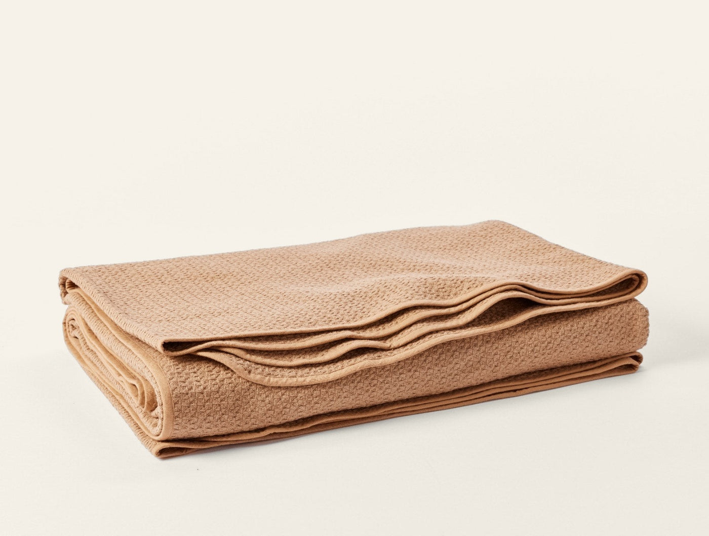 Coyuchi Honeycomb blanket in camel, folded to show woven texture and layered edges.