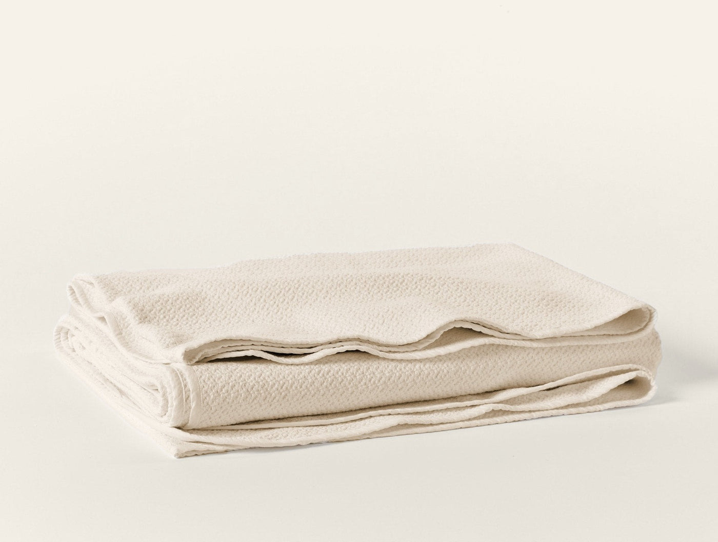 Ivory honeycomb-weave blanket neatly folded, showing textured surface detail.
