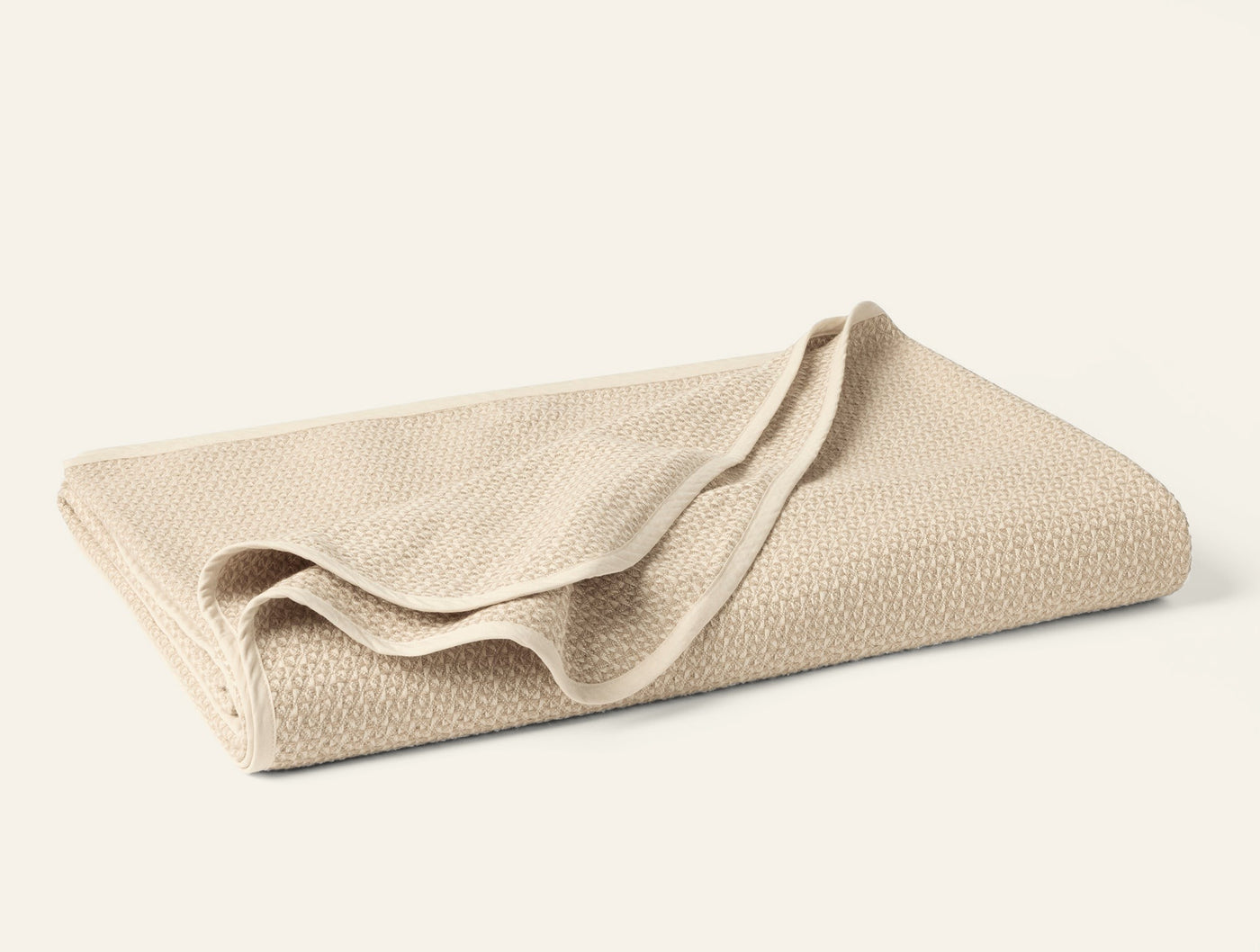 Folded ivory Coyuchi blanket showing honeycomb weave texture detail.