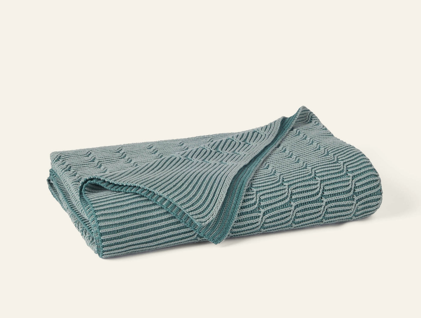 Folded Coyuchi Ivy Knit throw in teal, showing textured wave and ribbed knit pattern.