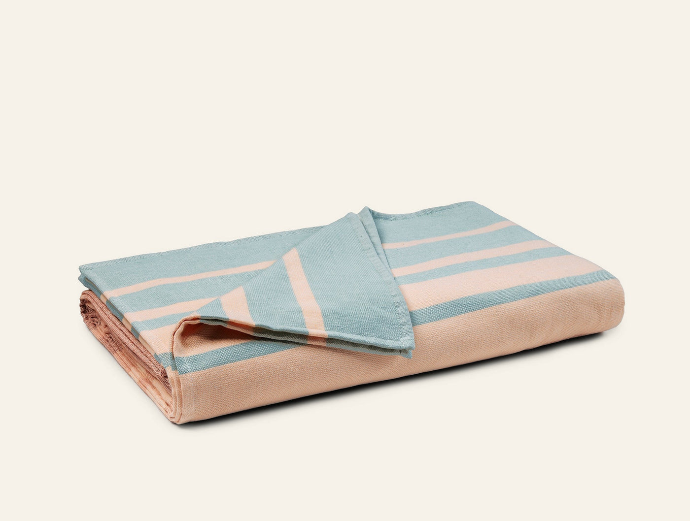 Coyuchi Laguna beach blanket in sage and blush, folded, showing stripe pattern on top face.
