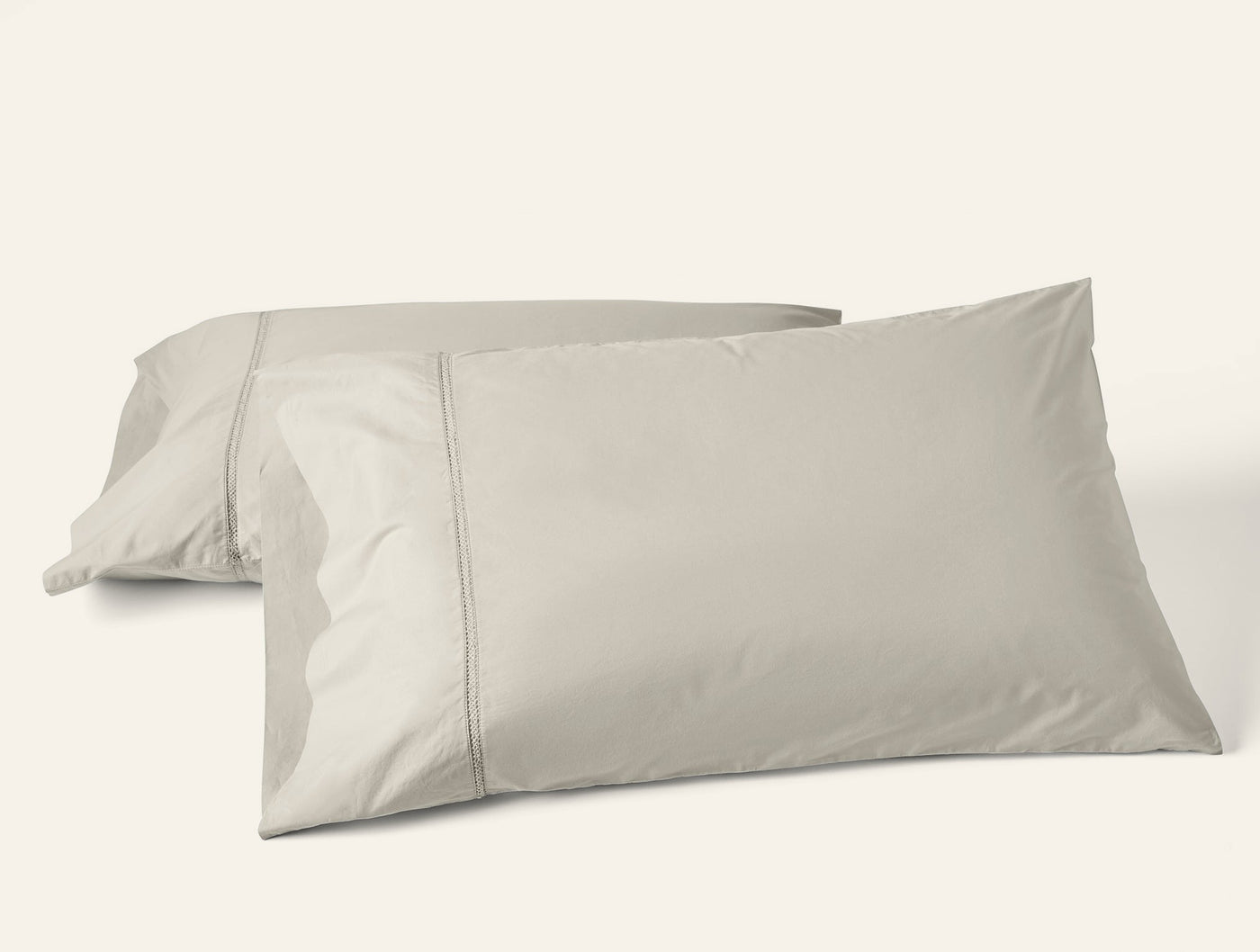 Two stone Coyuchi Lattice Percale pillowcases stacked, showing hemstitch detail.