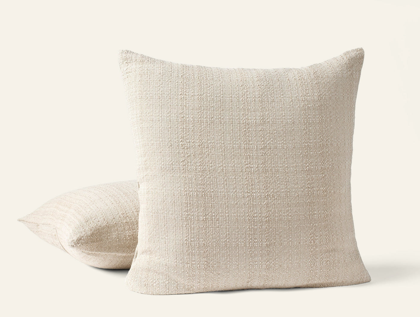 Pair of Coyuchi Lido ivory boucle-textured throw pillows, one upright, one flat.