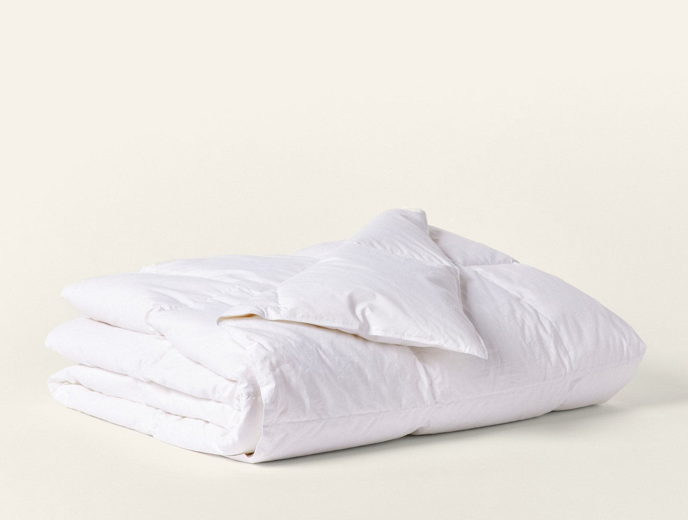 Coyuchi Lightweight Down duvet insert in white, neatly folded showing lofty fill.
