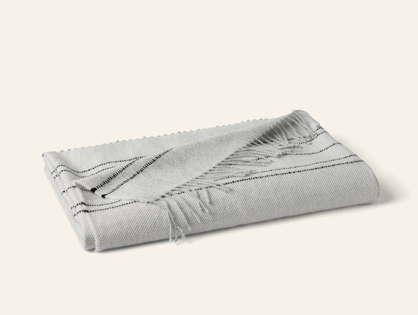 Folded silver and charcoal striped alpaca throw with fringe hem detail.