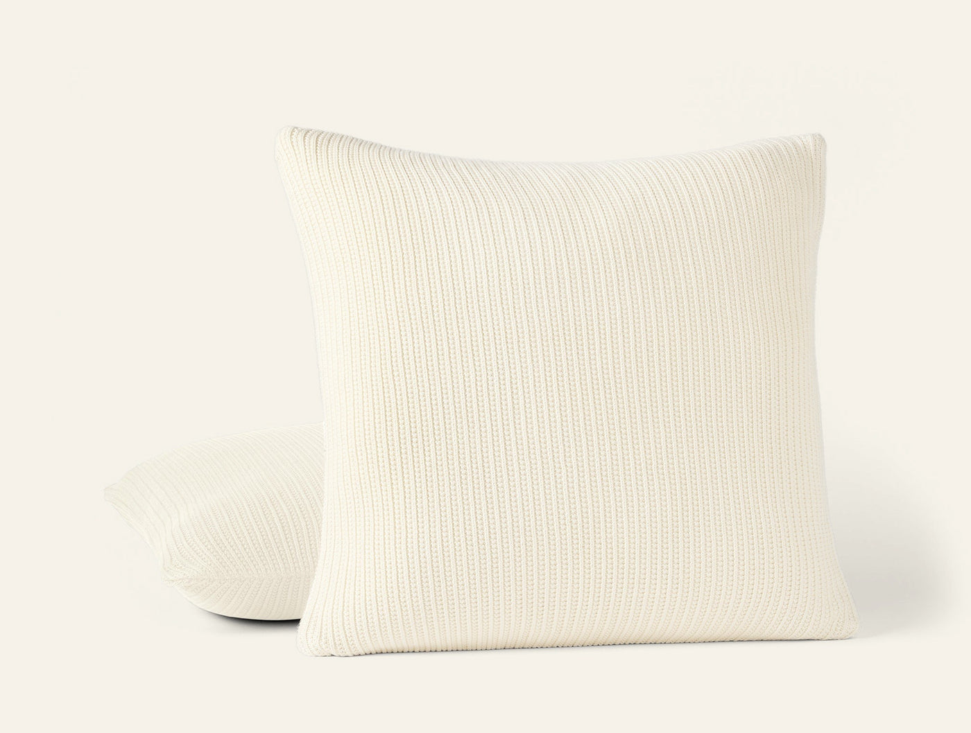 Ivory knit decorative pillow with vertical ribbed texture, two pillows stacked at an angle.
