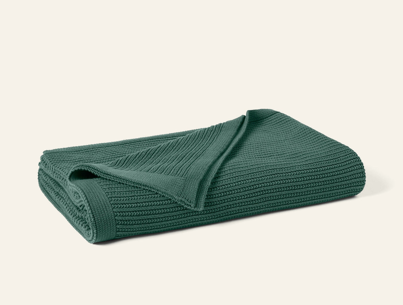 Folded forest green knit throw, showing ribbed texture and corner detail.
