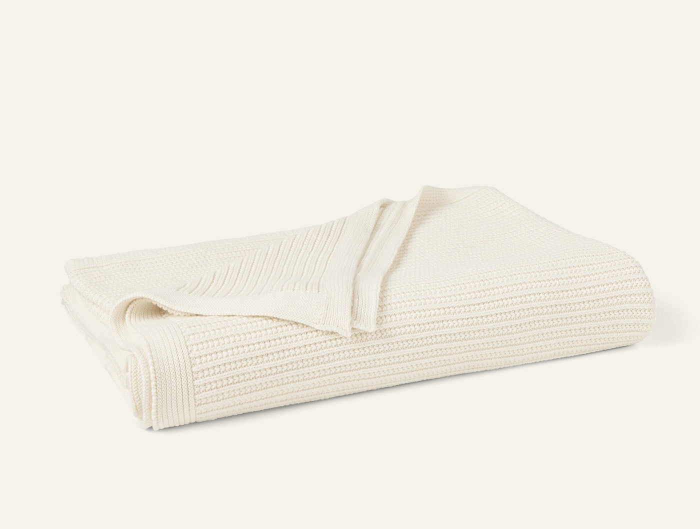 Ivory knit throw folded to show ribbed texture and natural weave detail.