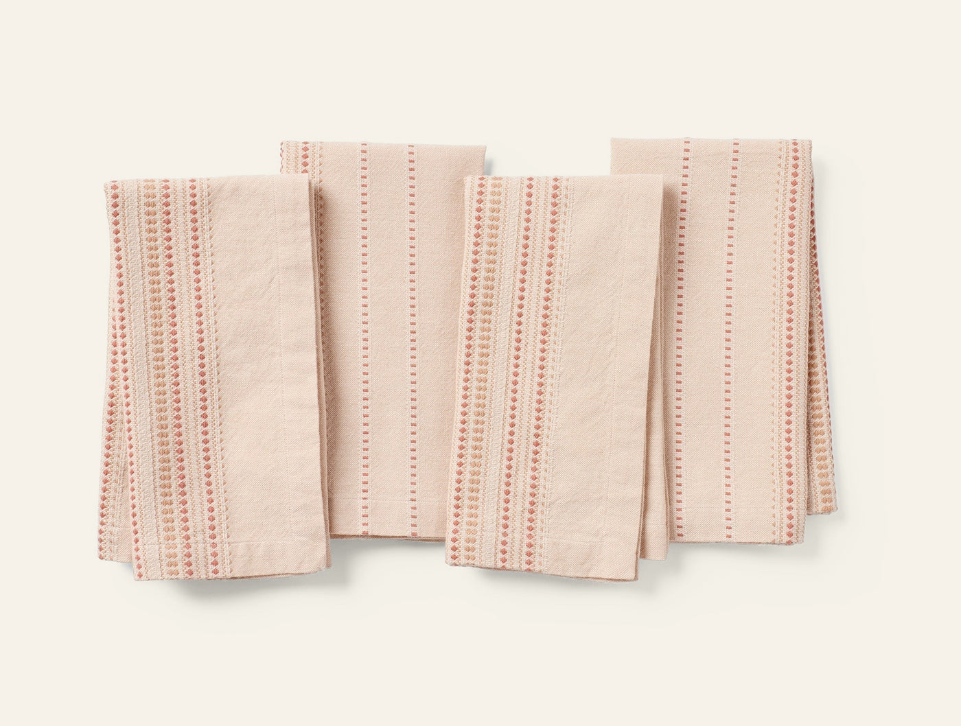 Coyuchi Lobos napkins in blush linen, set of four folded flat showing dotted coral stripe pattern.