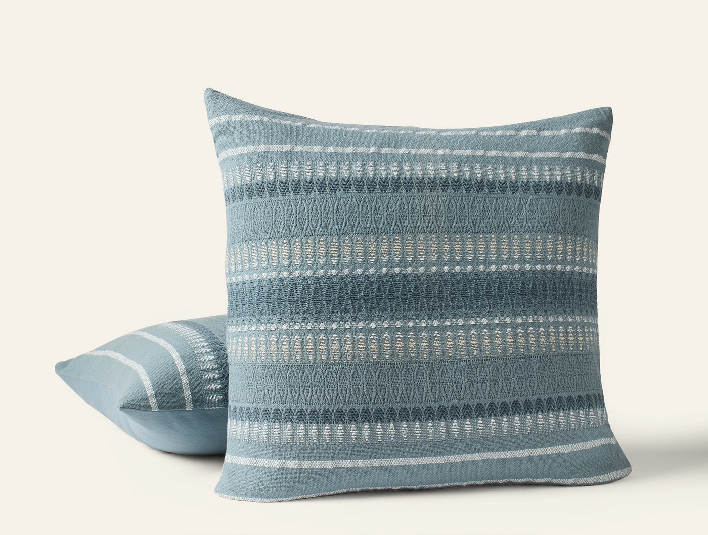 Coyuchi Lost Coast pillow in slate blue, showing front and back views with woven stripe detail.