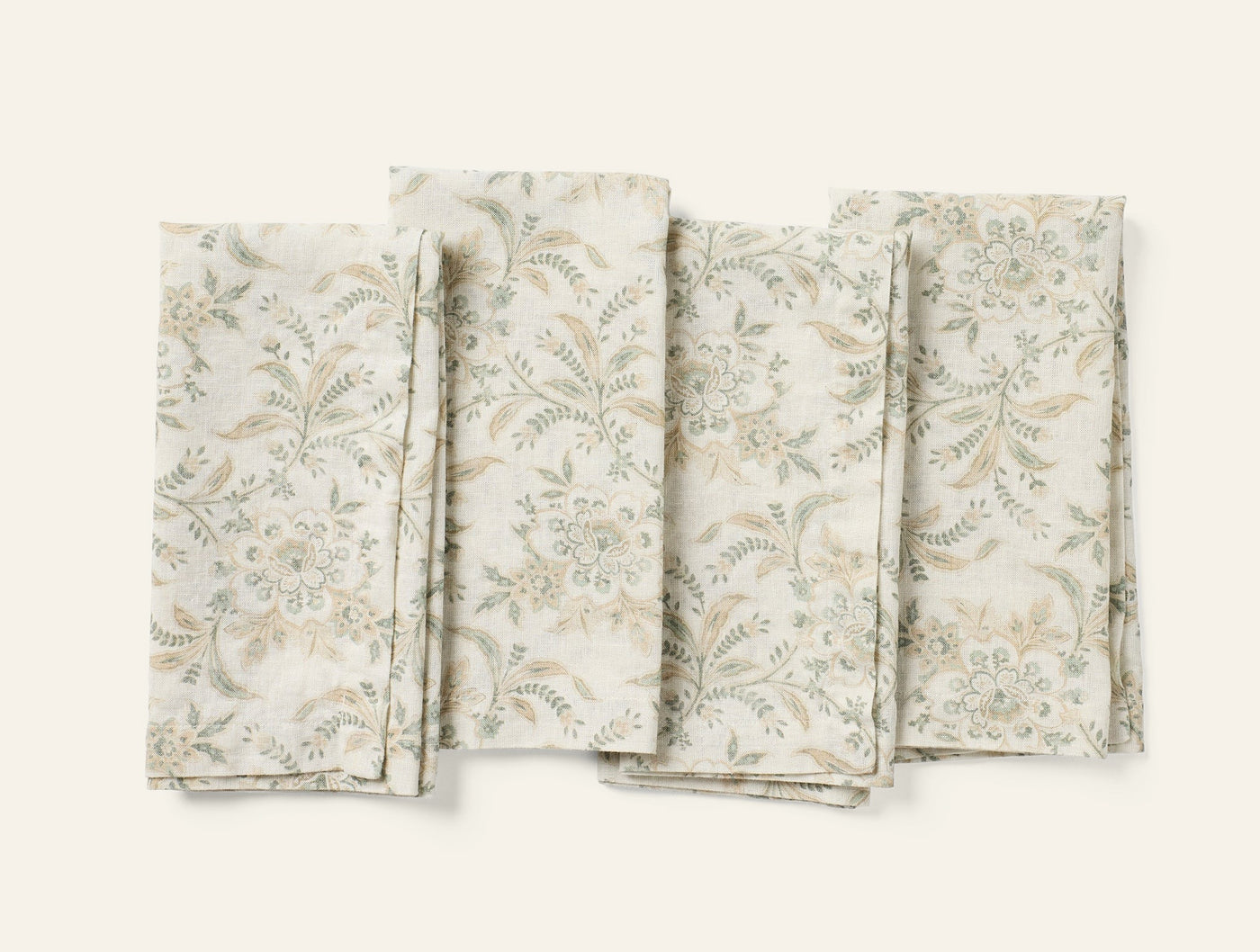 Four Coyuchi Marguerite Print napkins fanned flat, ivory with sage and taupe floral print.
