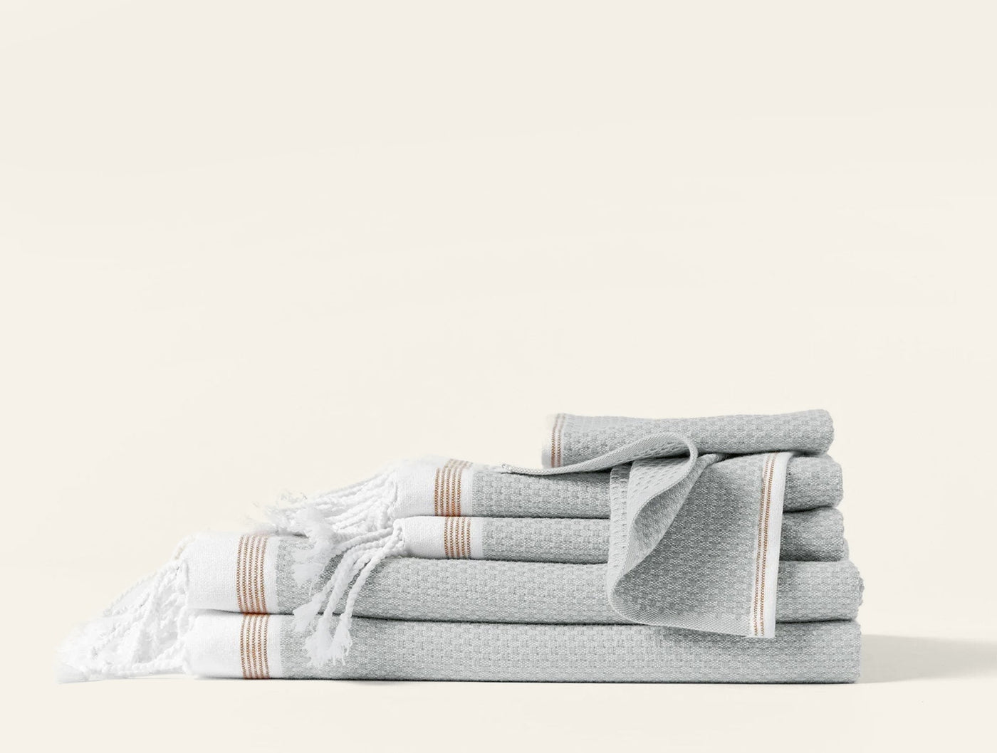 Coyuchi Mediterranean bath sheet set in mist, waffle weave with tan stripe trim and fringe detail.