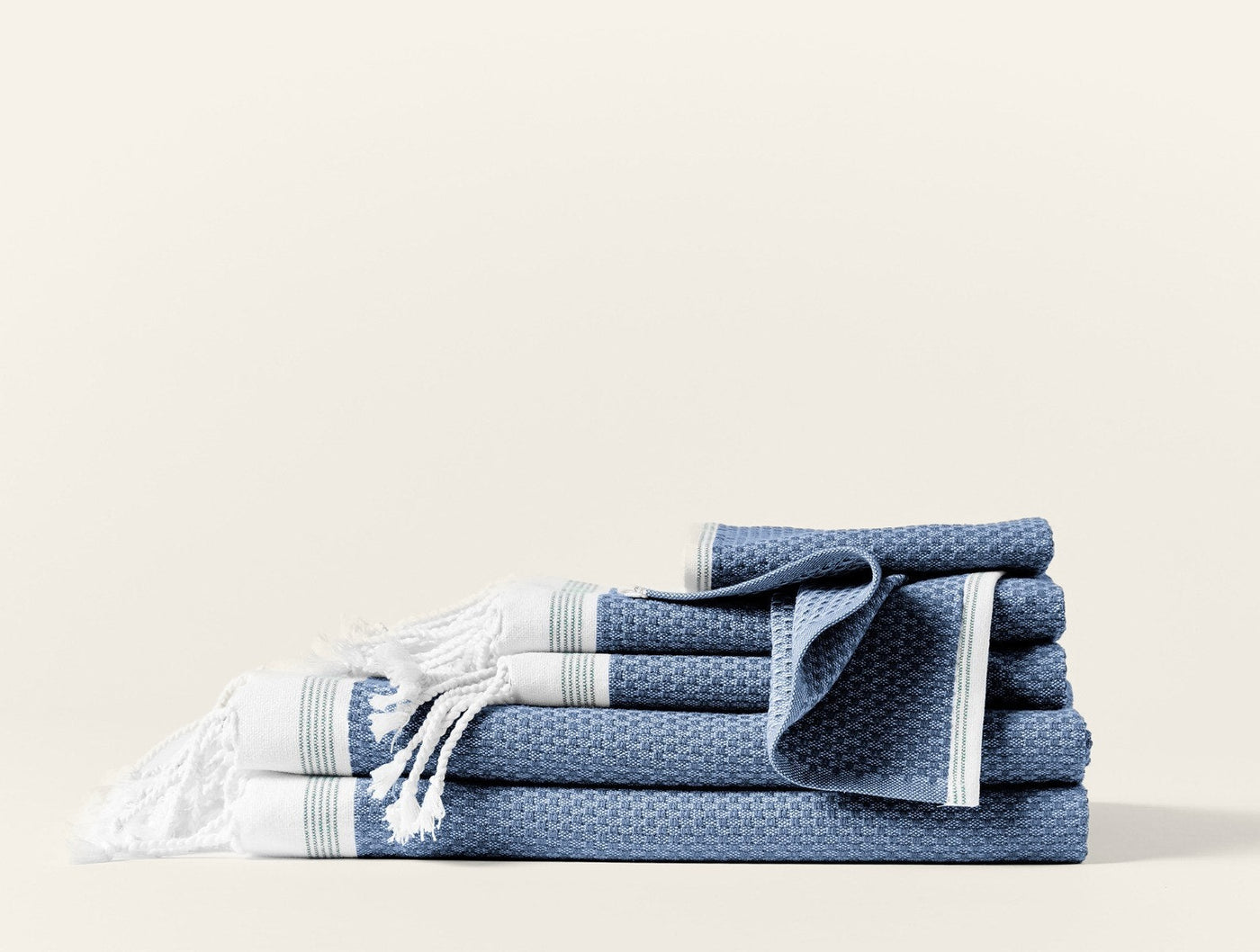 Coyuchi Mediterranean towel set in slate blue with white stripe trim and fringe detail.