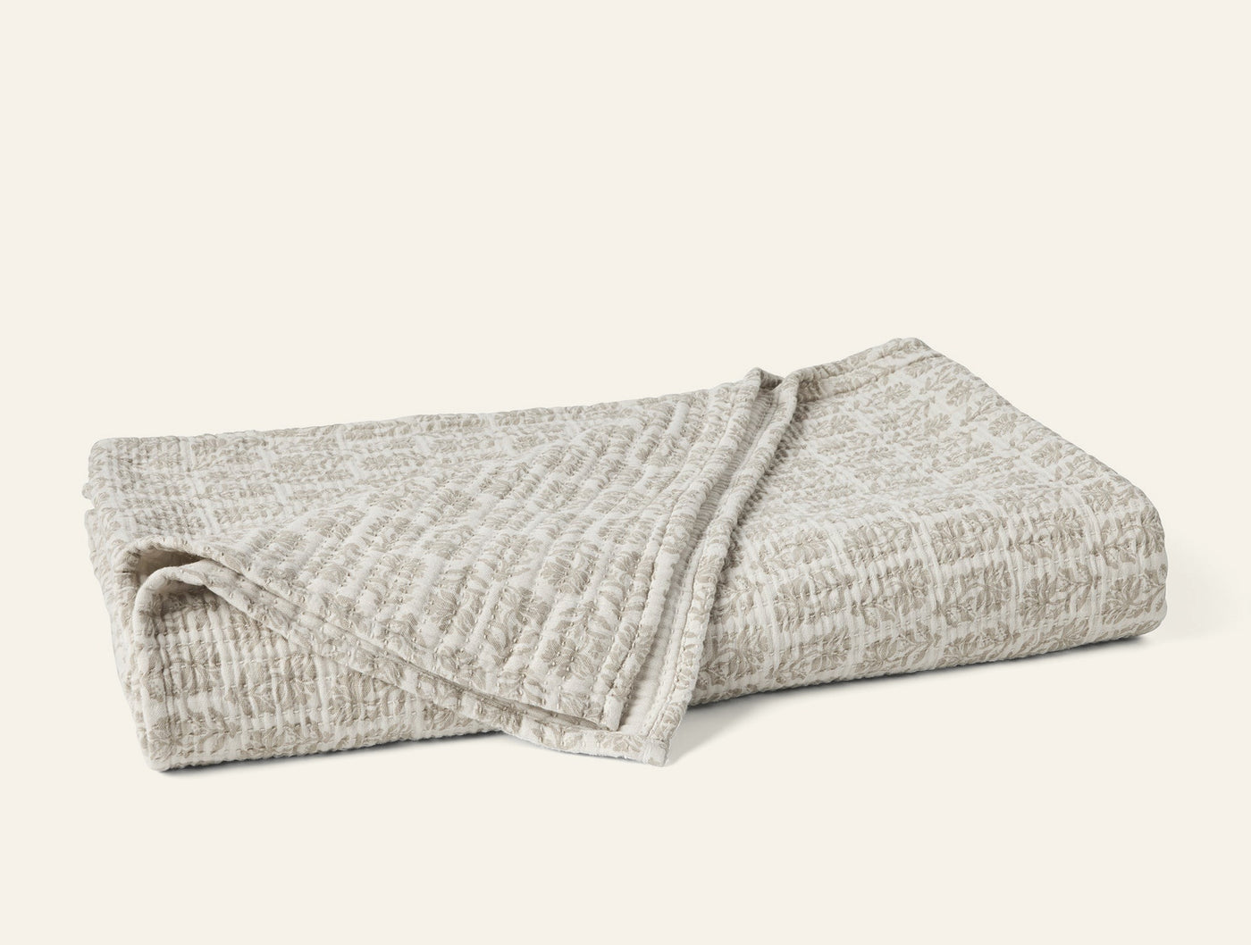 Close-up of folded Coyuchi Mirada Matelasse blanket in natural grey textured weave.