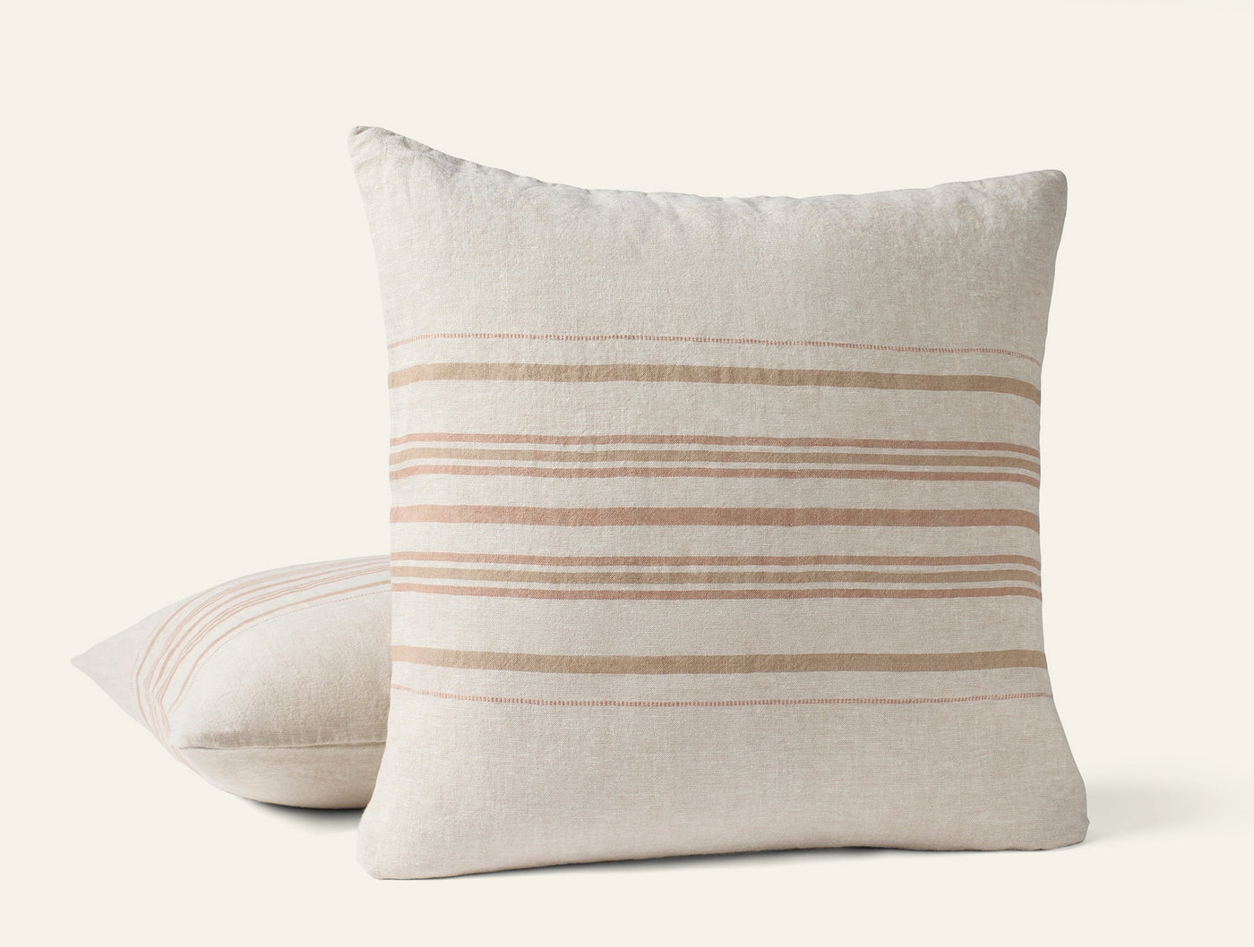Two Coyuchi Mojave Linen pillows stacked, ivory with warm tan horizontal stripes.