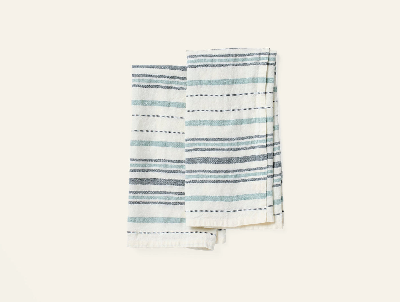 Pair of Coyuchi Mojave linen hand towels with slate and mist blue stripes and fringe hem.