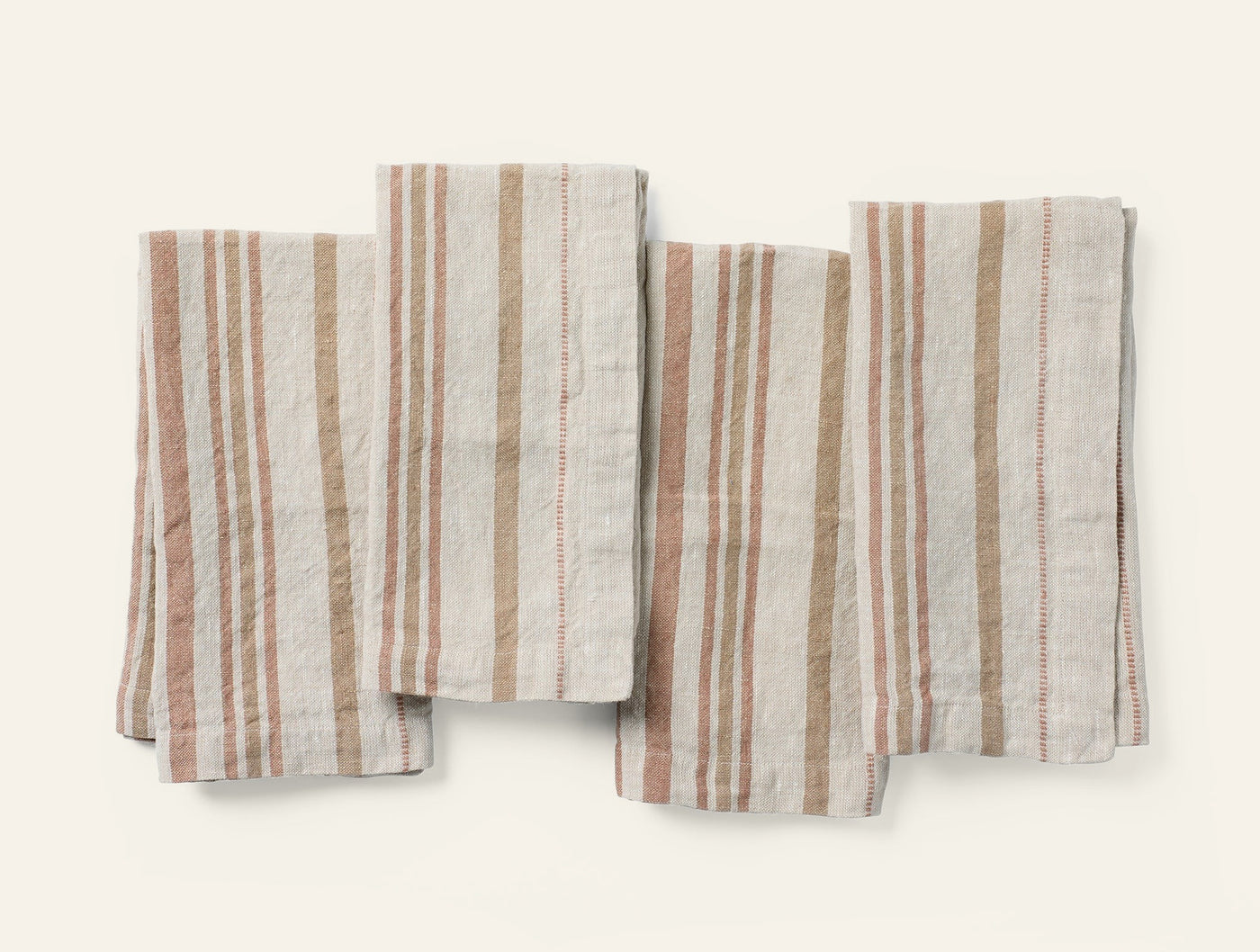 Four folded Coyuchi Mojave Linen napkins in terracotta and tan stripe, laid flat overhead.