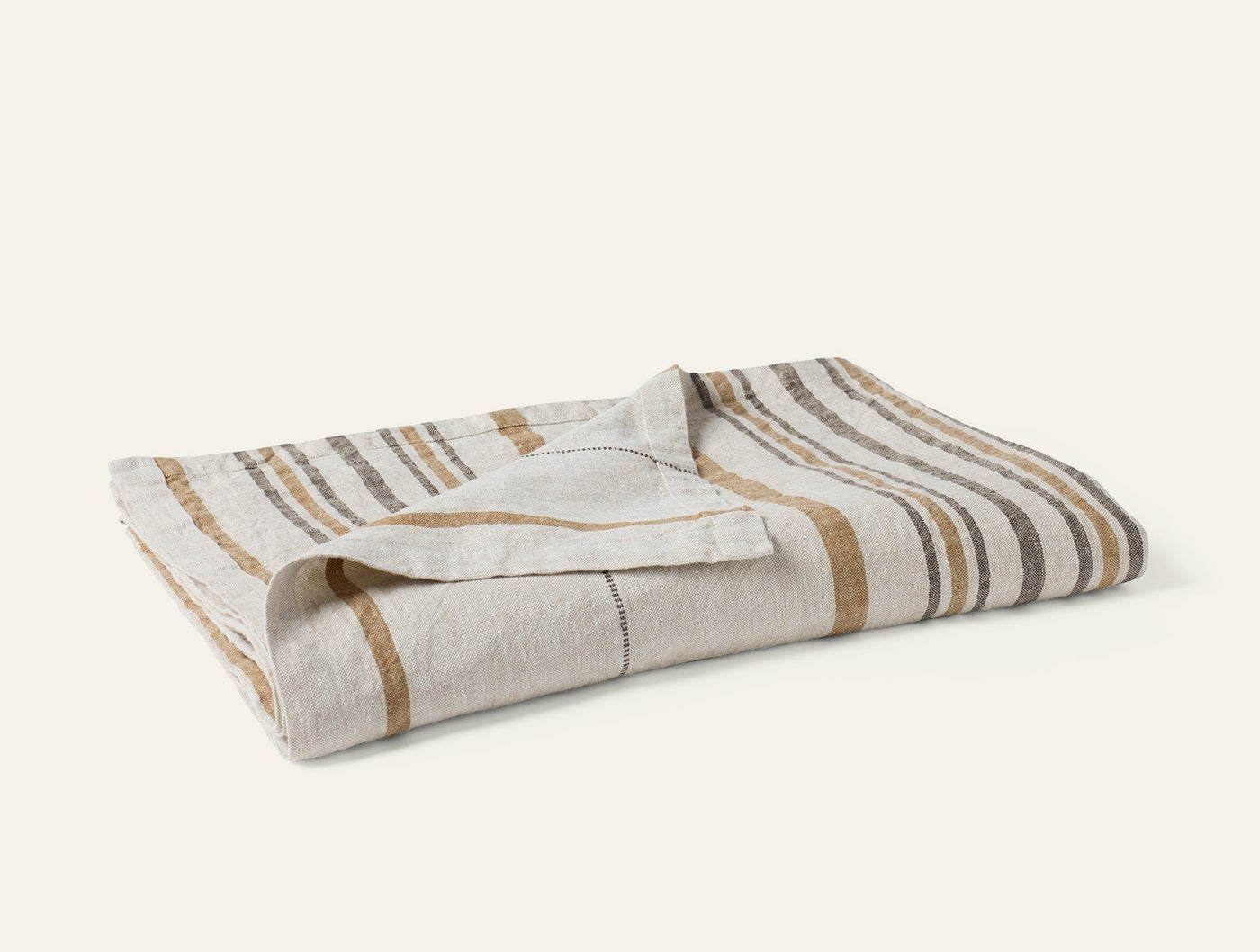 Coyuchi Mojave Linen Throw folded, natural stripe pattern in sand and slate.