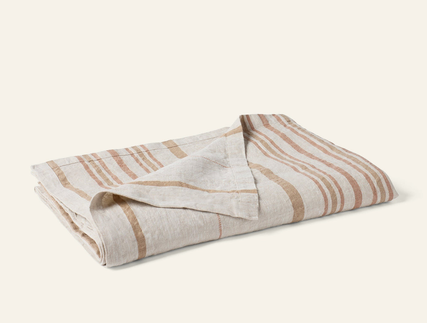 Close-up of folded Mojave Linen throw showing caramel stripe pattern on natural linen.