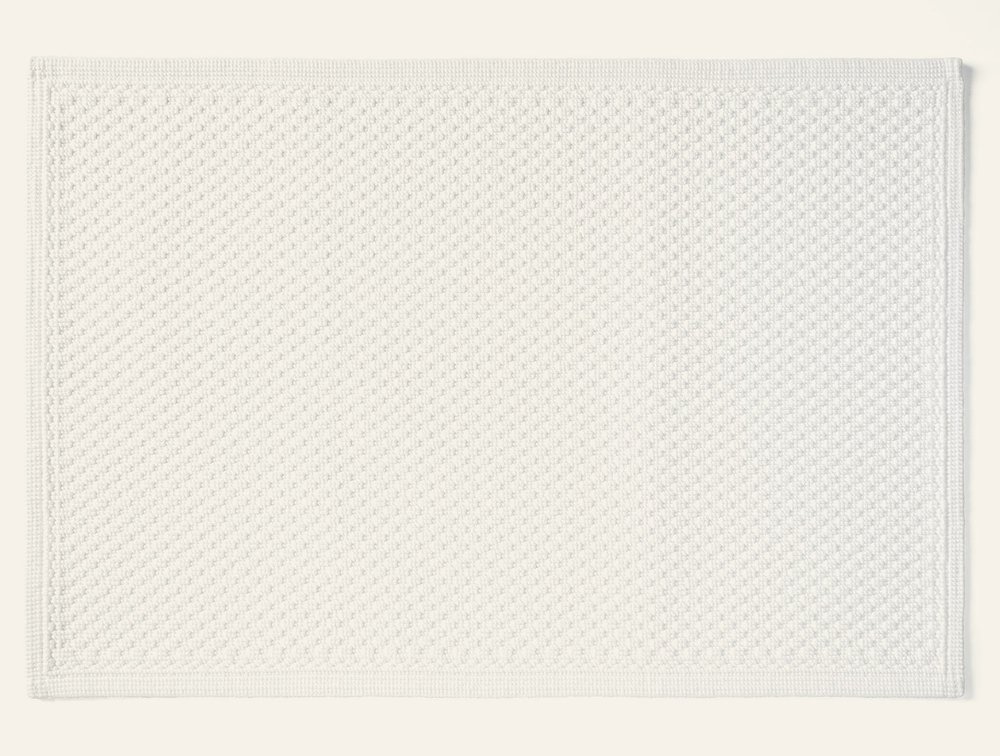 Coyuchi Moonstone bath rug in white with textured diamond weave pattern.