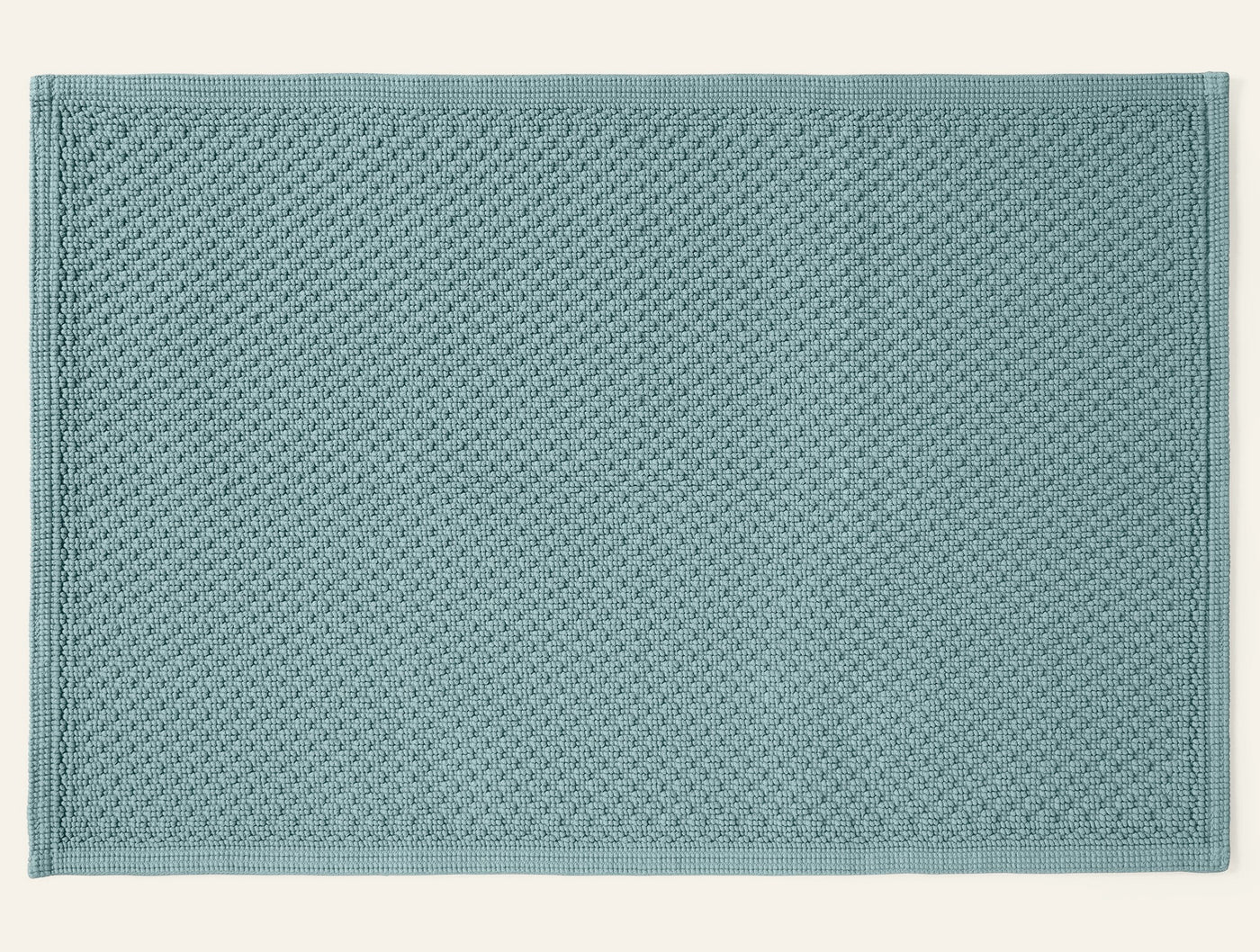 Coyuchi Moonstone bath rug in seafoam, overhead view showing waffle-weave texture.