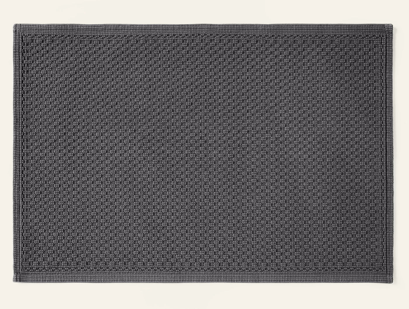 Coyuchi Moonstone bath rug in charcoal, showing full waffle-weave texture and border detail.