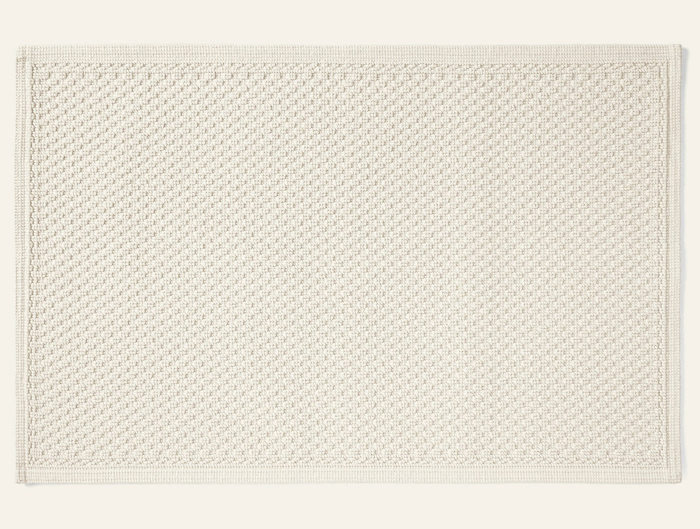 Coyuchi Moonstone bath rug in ivory, overhead flat lay showing woven texture and border detail.