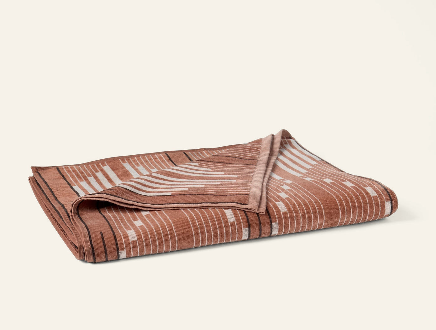 Folded terracotta Morelia beach towel showing geometric stripe pattern on reverse side.