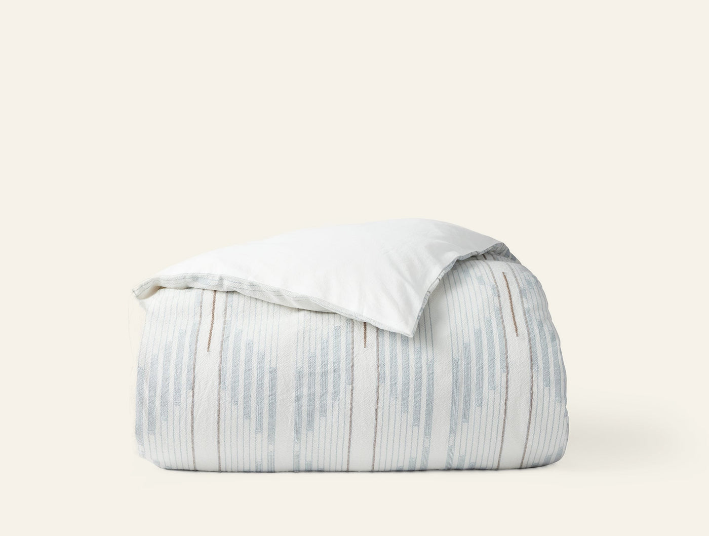 Coyuchi Morelia duvet cover folded, showing pale blue ikat stripe pattern against white background.