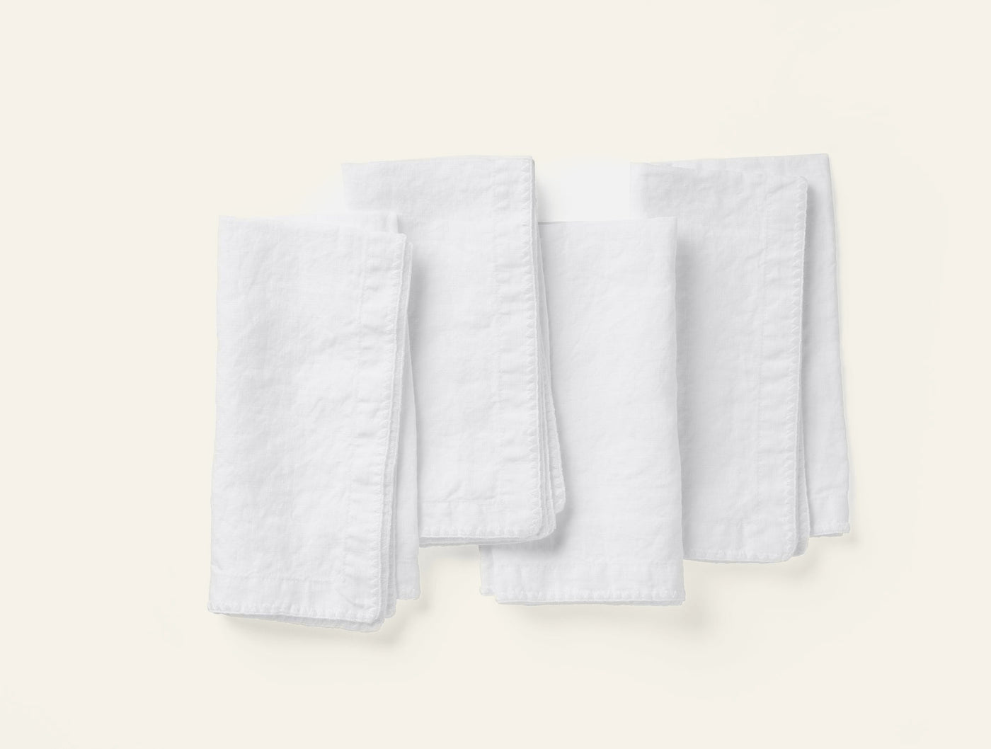 Coyuchi Olivos Embroidered Linen cocktail napkins in white, set of four folded.
