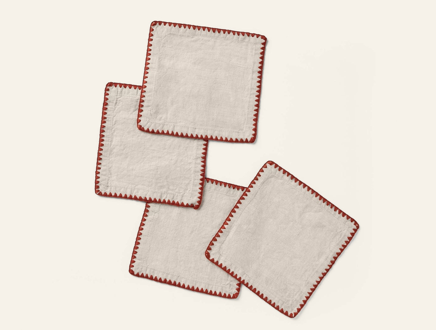 Close-up of four Coyuchi Olivos linen napkins with red blanket-stitch embroidered edges, fanned flat.