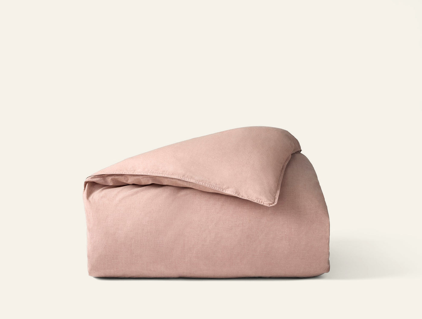 Coyuchi Crinkled Percale duvet cover folded, showing textured blush fabric surface.