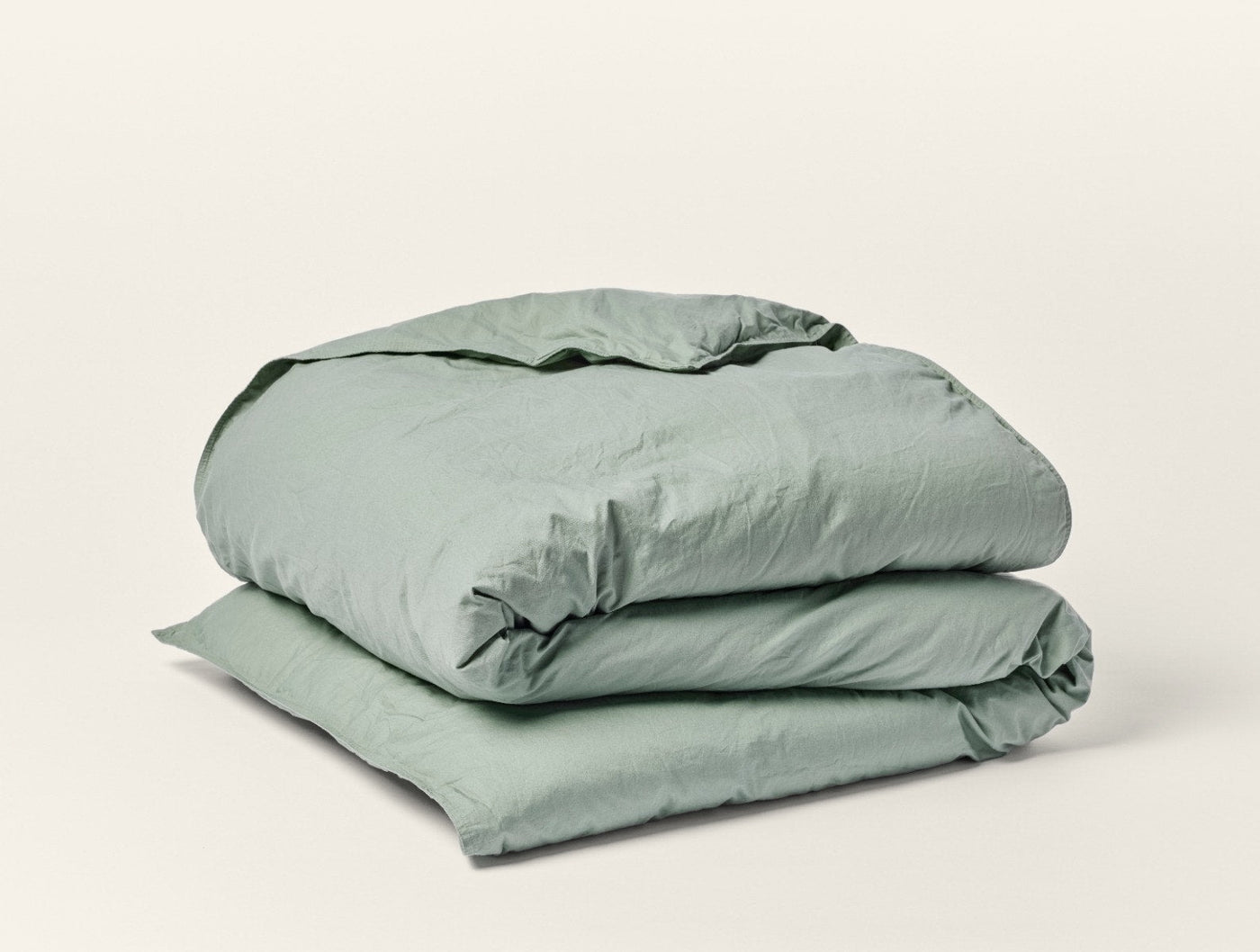 Sage green Coyuchi Crinkled Percale duvet cover folded, showing natural crinkled texture.