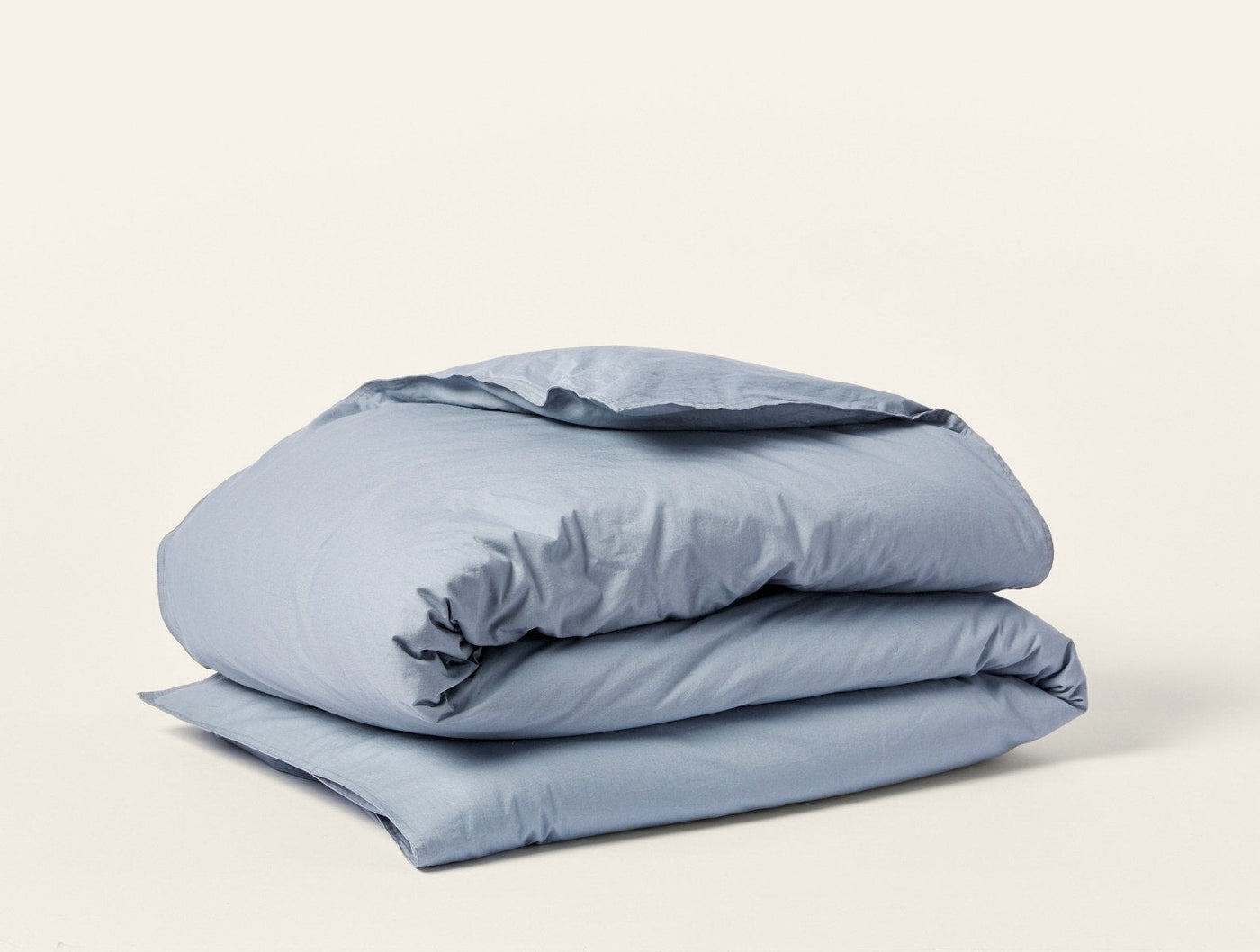 Coyuchi Crinkled Percale duvet cover folded neatly, shown in slate blue.