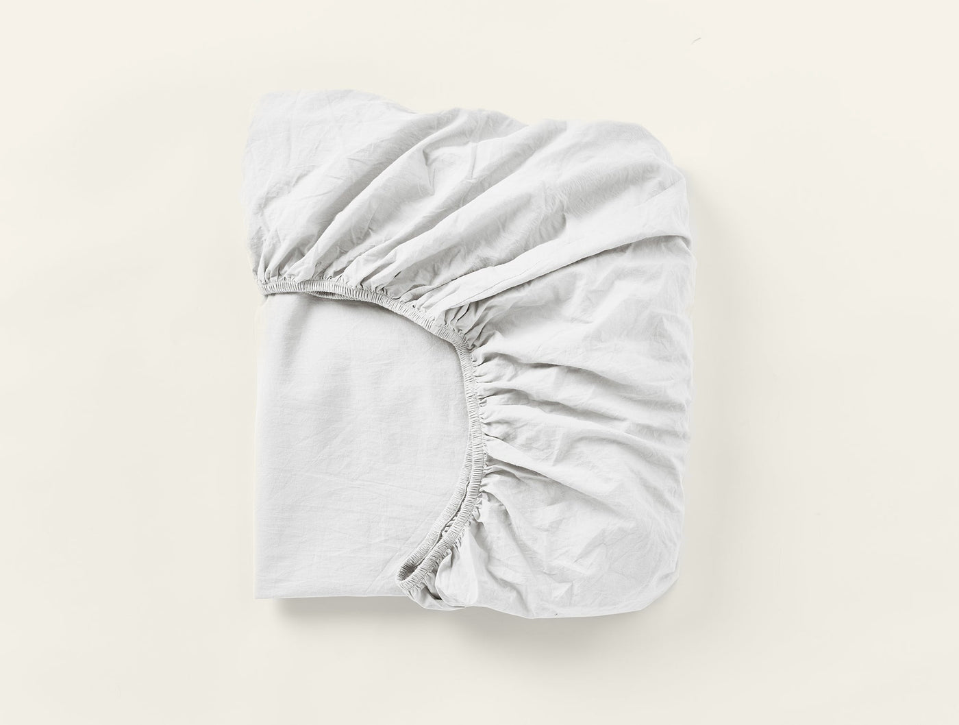 Coyuchi Crinkled Percale fitted sheet in white, folded flat showing elasticated corners.