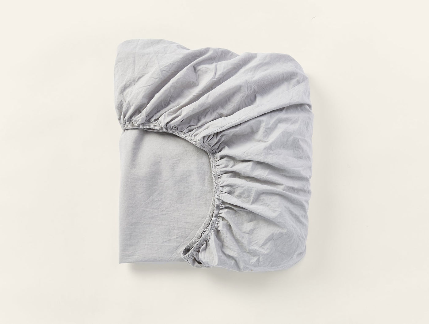 Folded silver grey fitted sheet showing elasticized corner detail.
