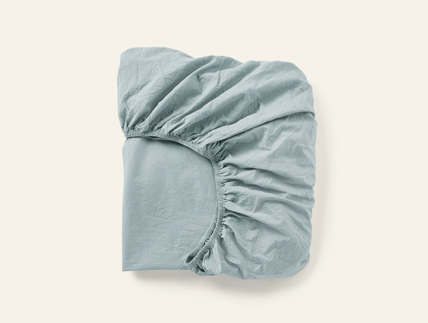 Folded sage fitted sheet showing elasticated corner detail against white background.