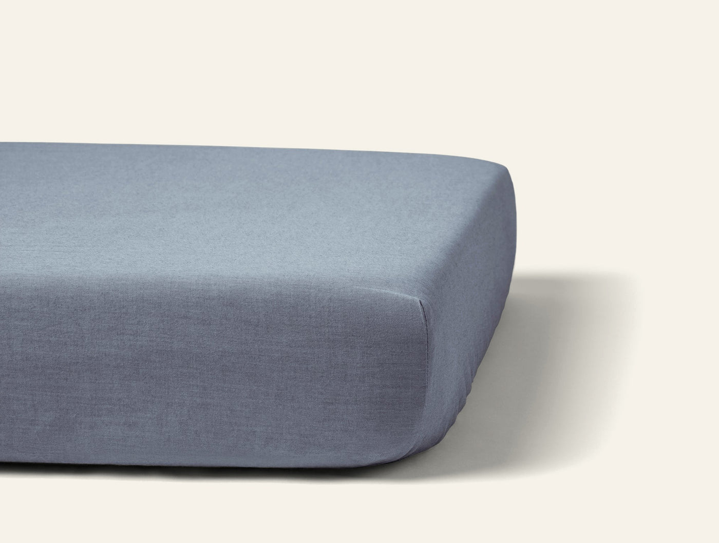 Coyuchi Crinkled Percale fitted sheet in slate blue, shown fitted tautly on a mattress.