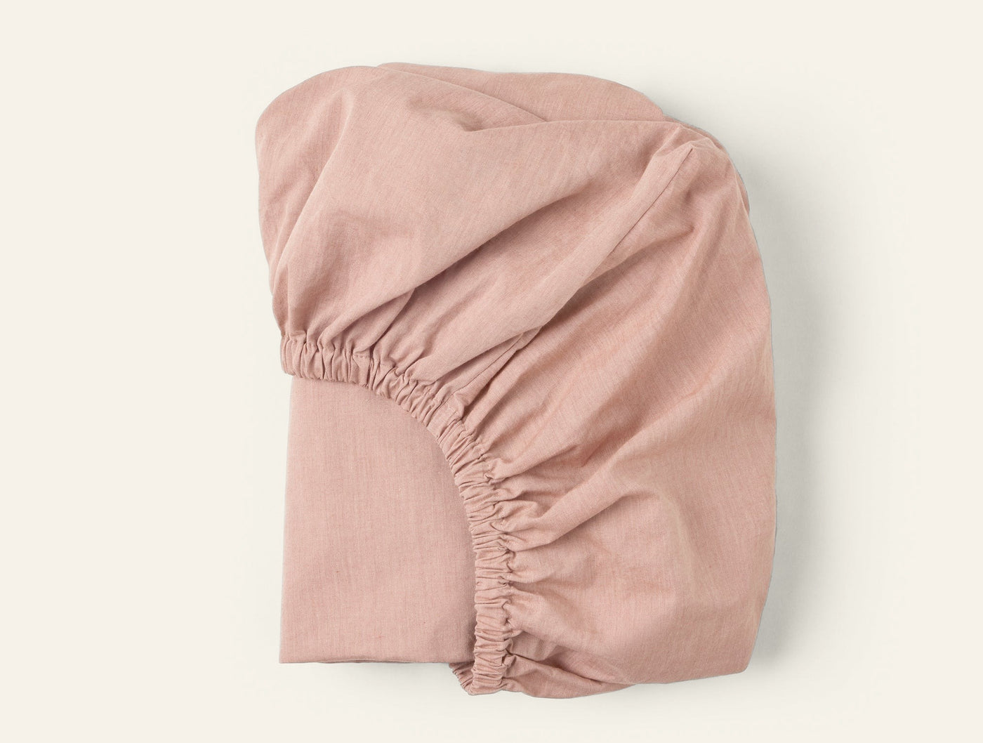 Coyuchi Crinkled Percale fitted sheet in blush, showing elasticized corner detail.